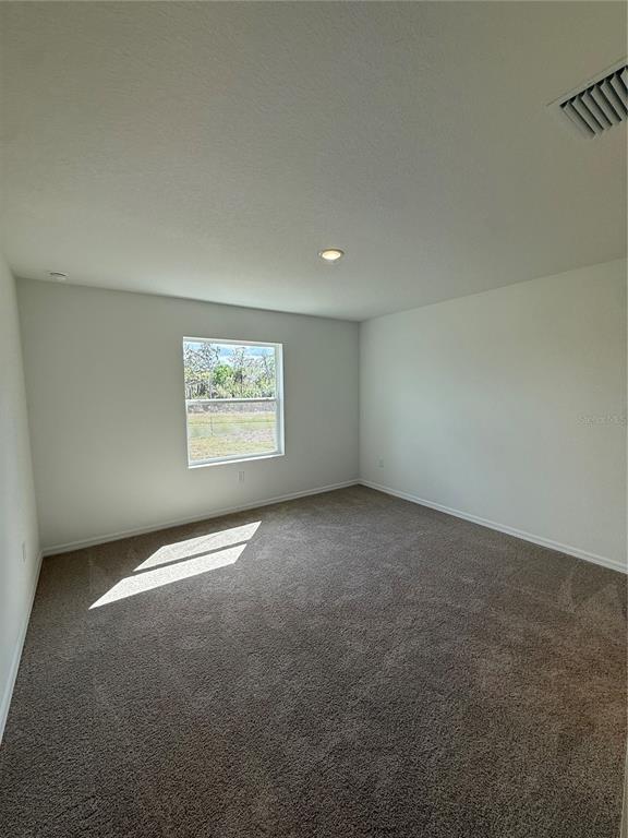 A bedroom with white walls, beige carpet, a single window, and a recessed ceiling light — 13044 SASSAFRAS TRAIL, PARRISH, FL
