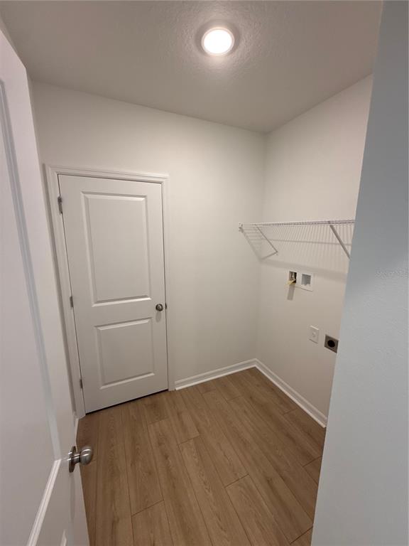 A laundry room with wood-look tile flooring, a white door, and a wire wall shelf — 13044 SASSAFRAS TRAIL, PARRISH, FL