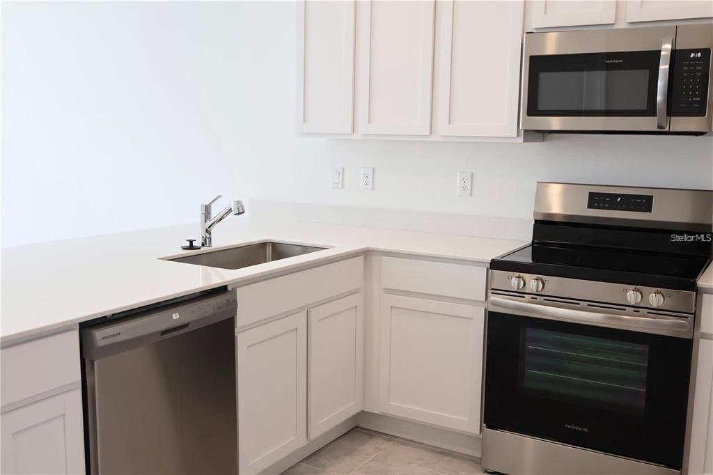 A kitchen features white cabinets, stainless steel appliances, and white countertops with a sink — 2452 SKYLINE LOOP, KISSIMMEE, FL