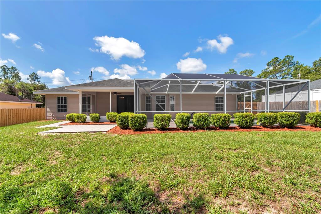 The backyard features a screened-in pool enclosure, a concrete patio, and manicured hedges — 63 PECAN PASS, OCALA, FL