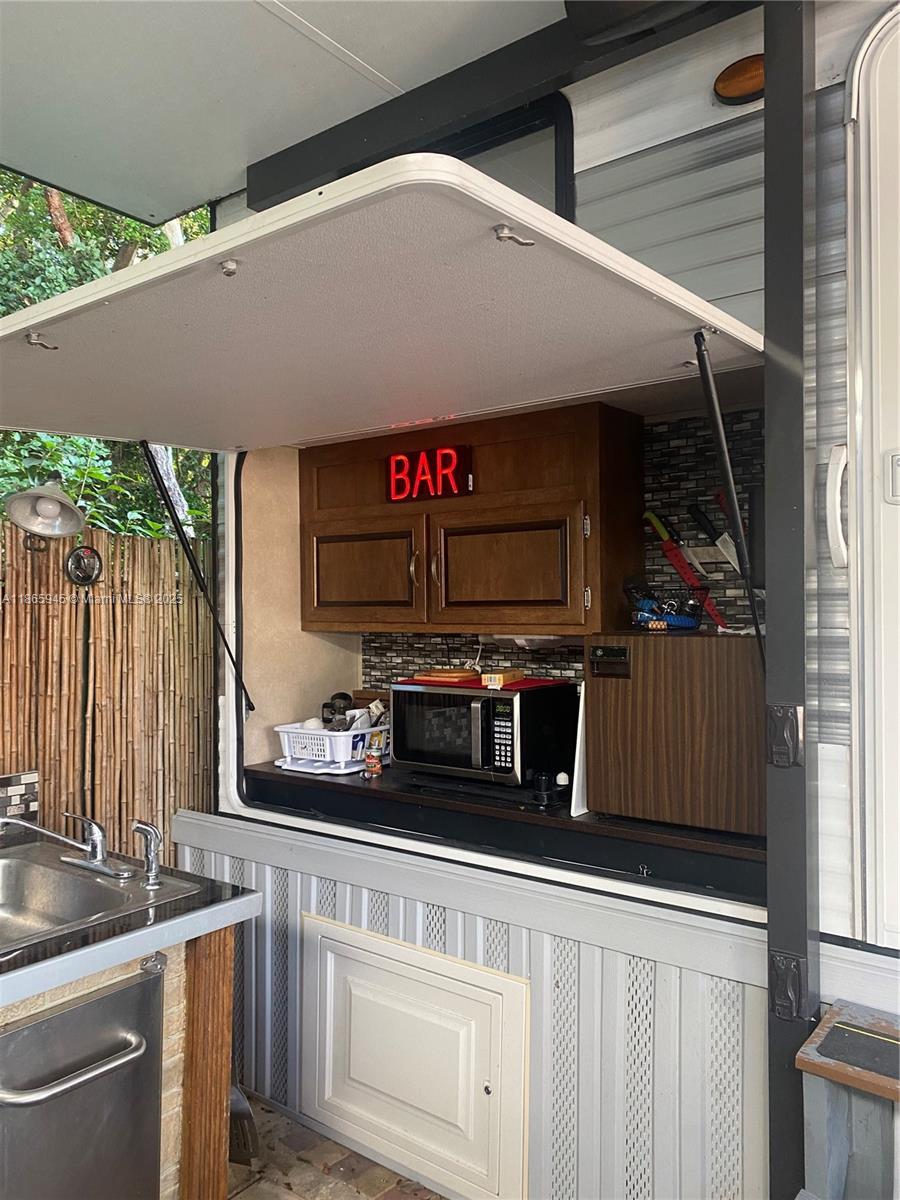 An outdoor kitchen area features a microwave, small refrigerator, and a neon bar sign — 325 Calusa St #120, Key Largo FL 33037, KEY LARGO, FL