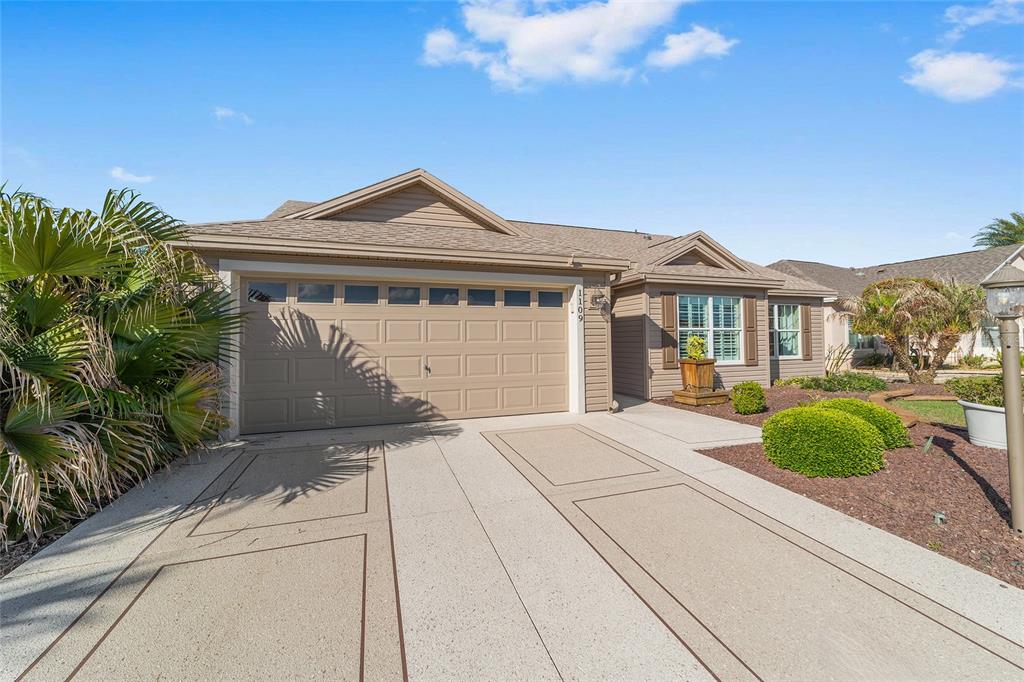 A single-story house with a beige garage and a decorative concrete driveway — 1109 ALCOVE LOOP, THE VILLAGES, FL