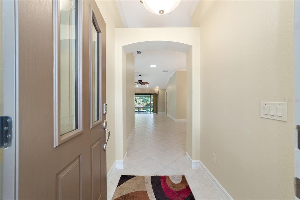 A view from an open front door into a tiled foyer leading to a living area — 1109 ALCOVE LOOP, THE VILLAGES, FL