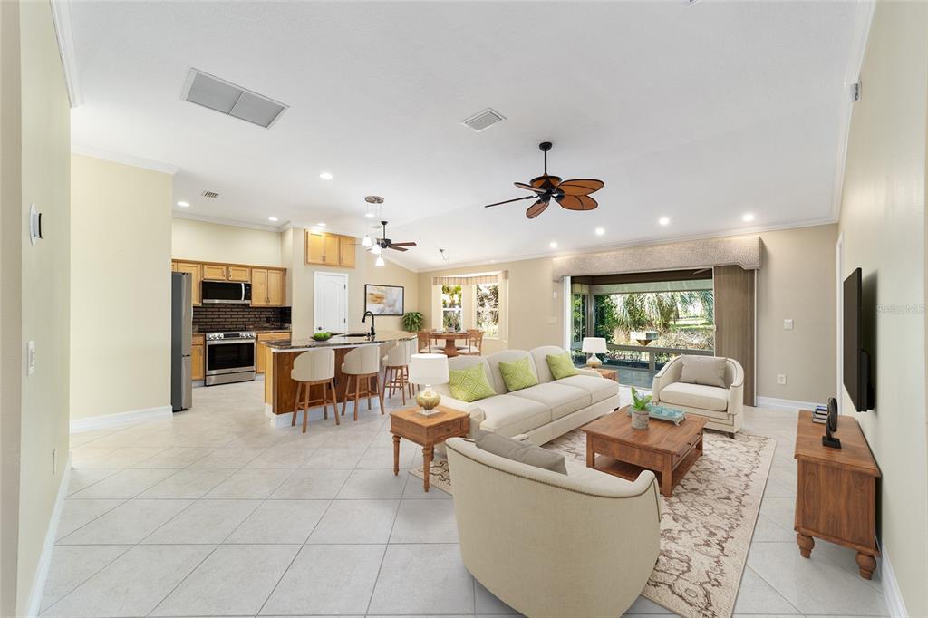 An open-concept living room and kitchen featuring tile floors, a ceiling fan, and sliding doors — 1109 ALCOVE LOOP, THE VILLAGES, FL