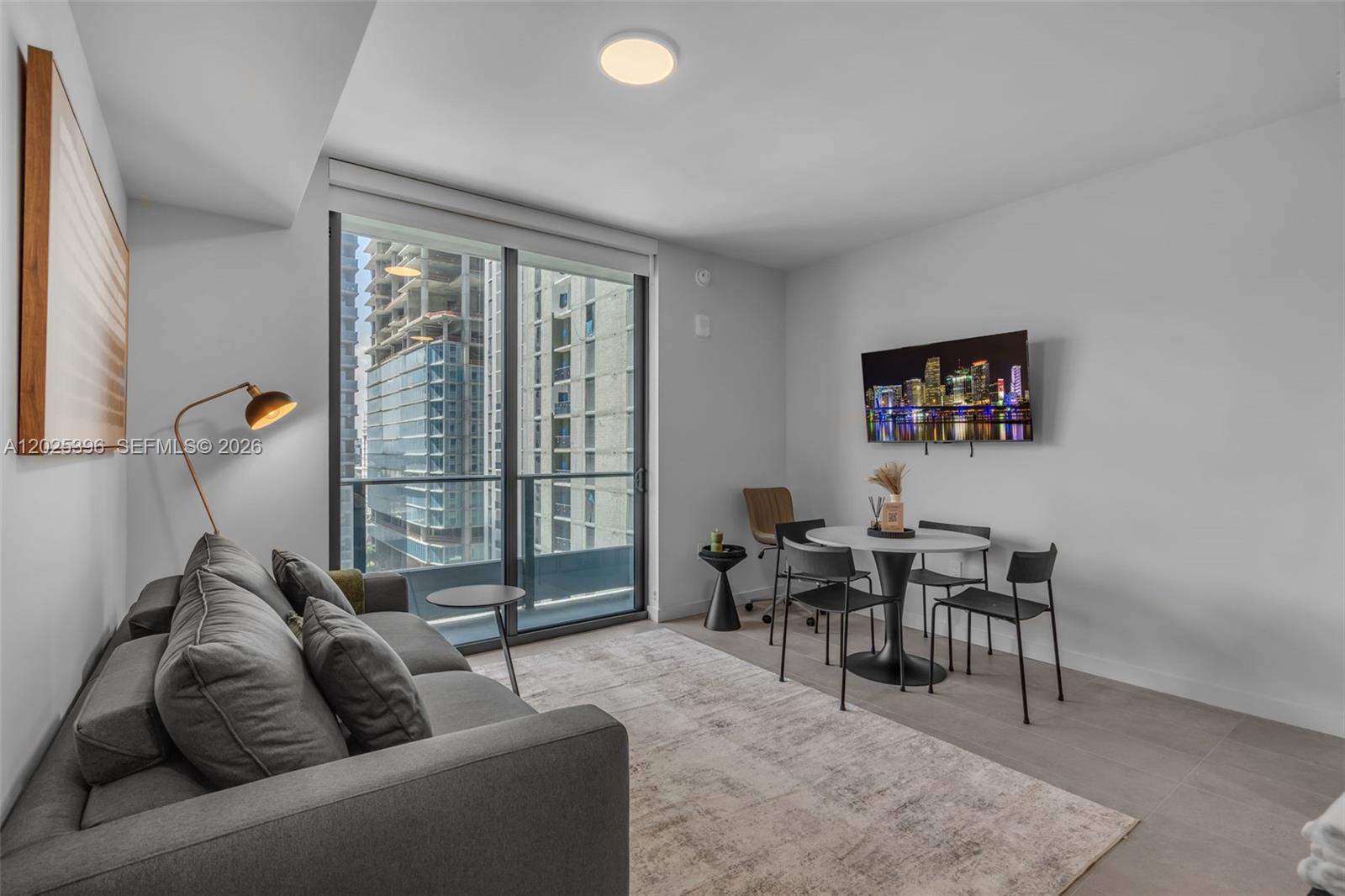 A modern living room features a gray sofa, a dining set, and floor-to-ceiling windows — 121 NE 5th St # 2107, Miami FL 33132, MIAMI, FL