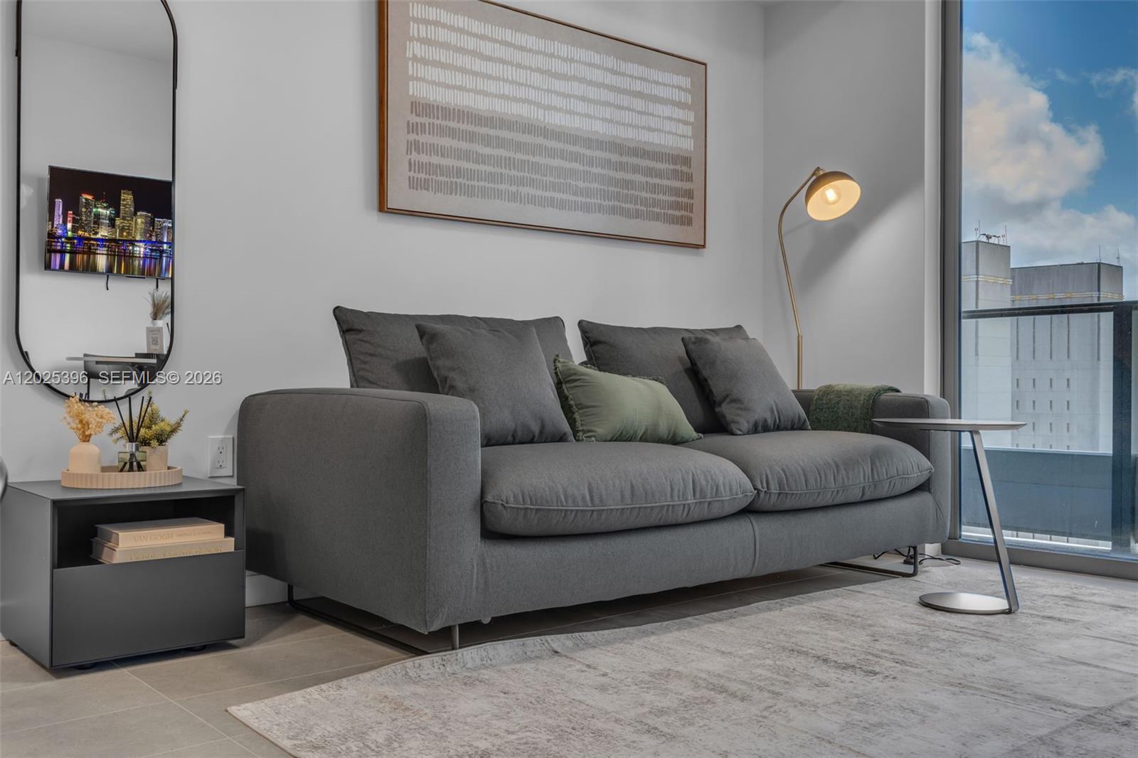A gray sofa sits on a rug in a living room with a floor lamp — 121 NE 5th St # 2107, Miami FL 33132, MIAMI, FL
