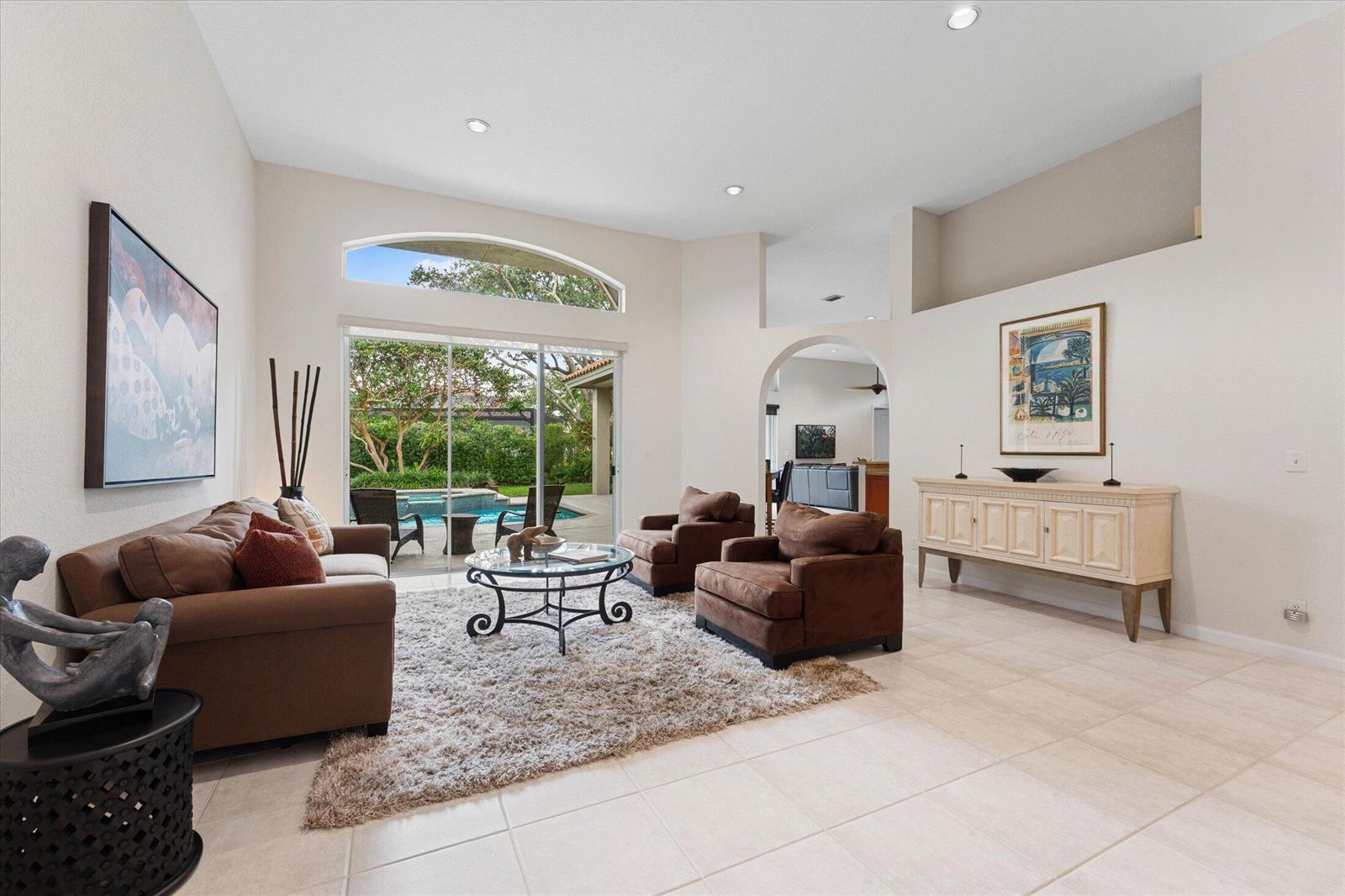 A living room with brown furniture, a shaggy rug, and sliding doors opening to a pool — 10331 NW 62nd Drive, Parkland FL 33076, PARKLAND, FL