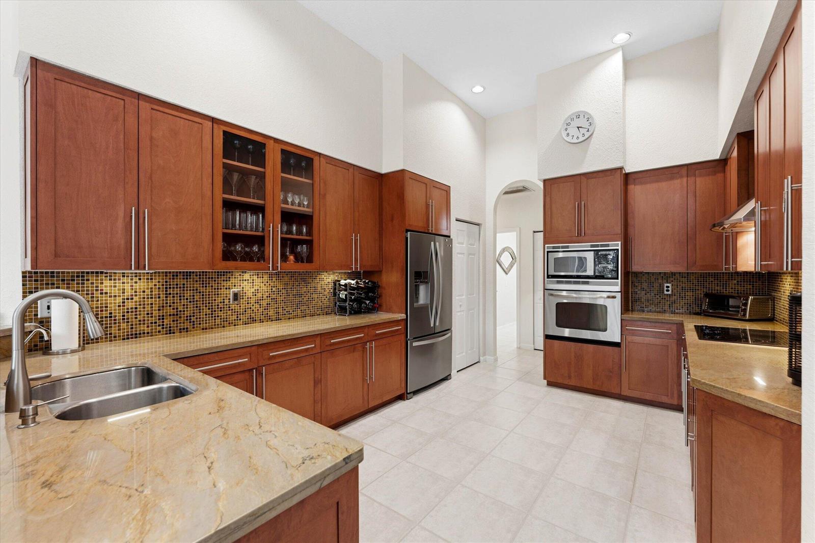 A kitchen with wood cabinets, stainless steel appliances, granite countertops, and a mosaic tile backsplash — 10331 NW 62nd Drive, Parkland FL 33076, PARKLAND, FL