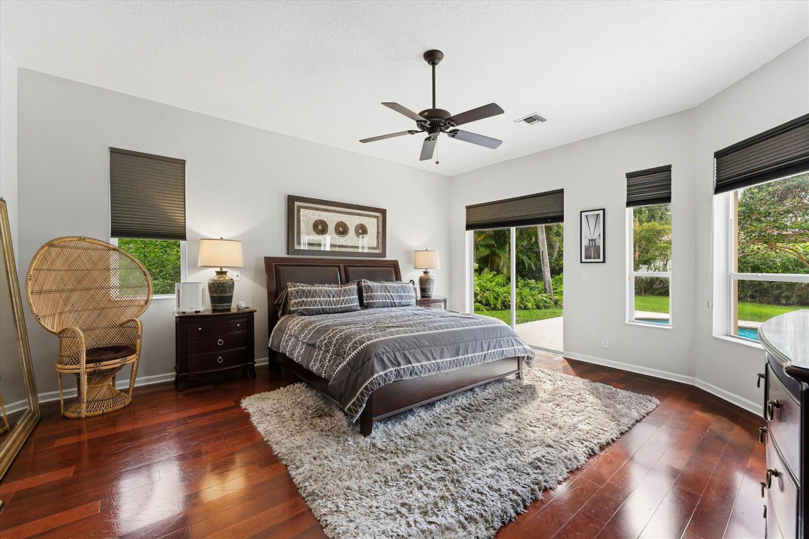 A bedroom features a dark wood bed, a shaggy rug, and a wicker peacock chair — 10331 NW 62nd Drive, Parkland FL 33076, PARKLAND, FL