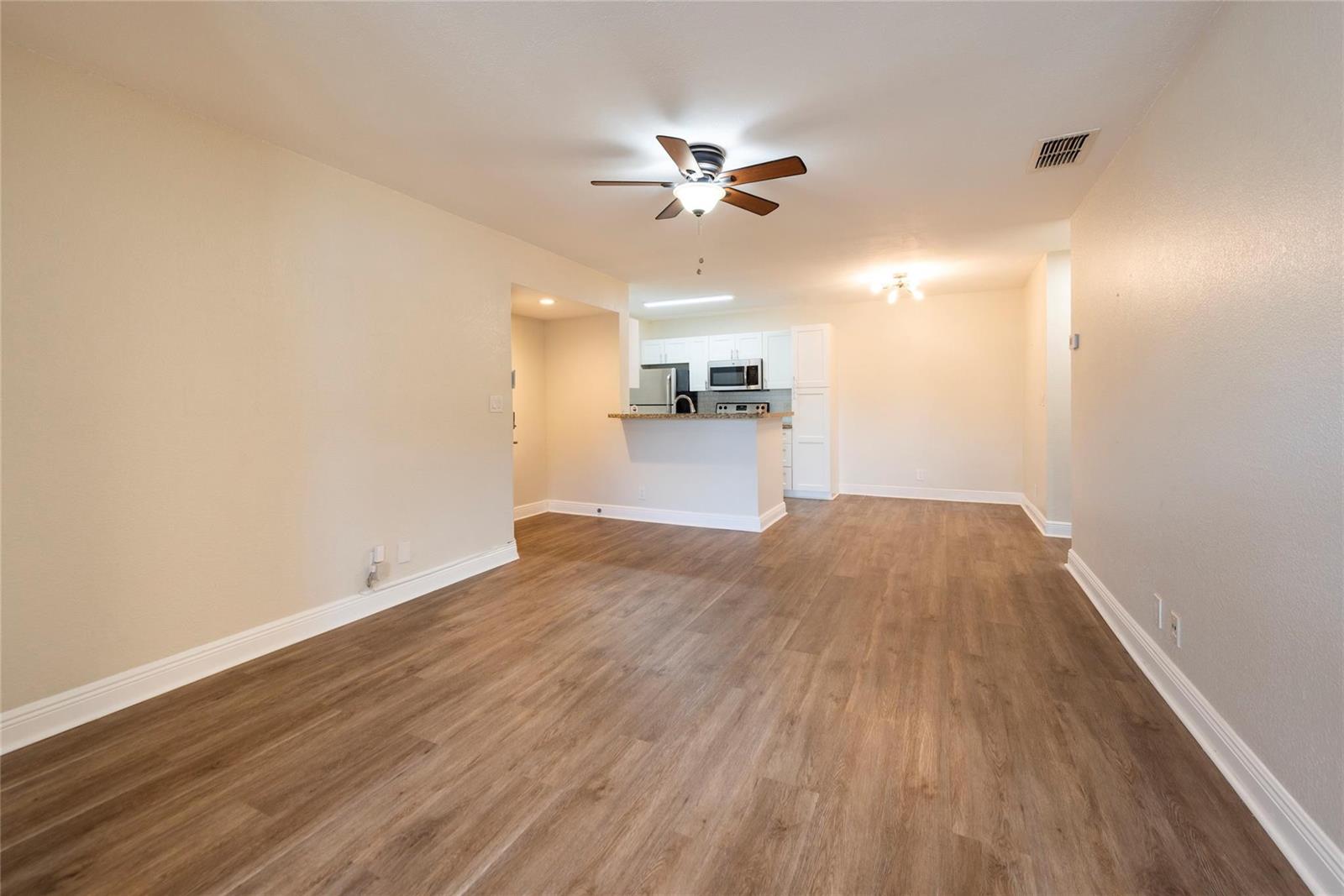 An open-concept living area features wood-look flooring, a ceiling fan, and a kitchen with white cabinets — 2906 S University Drive # 10104, Davie FL 33328, DAVIE, FL