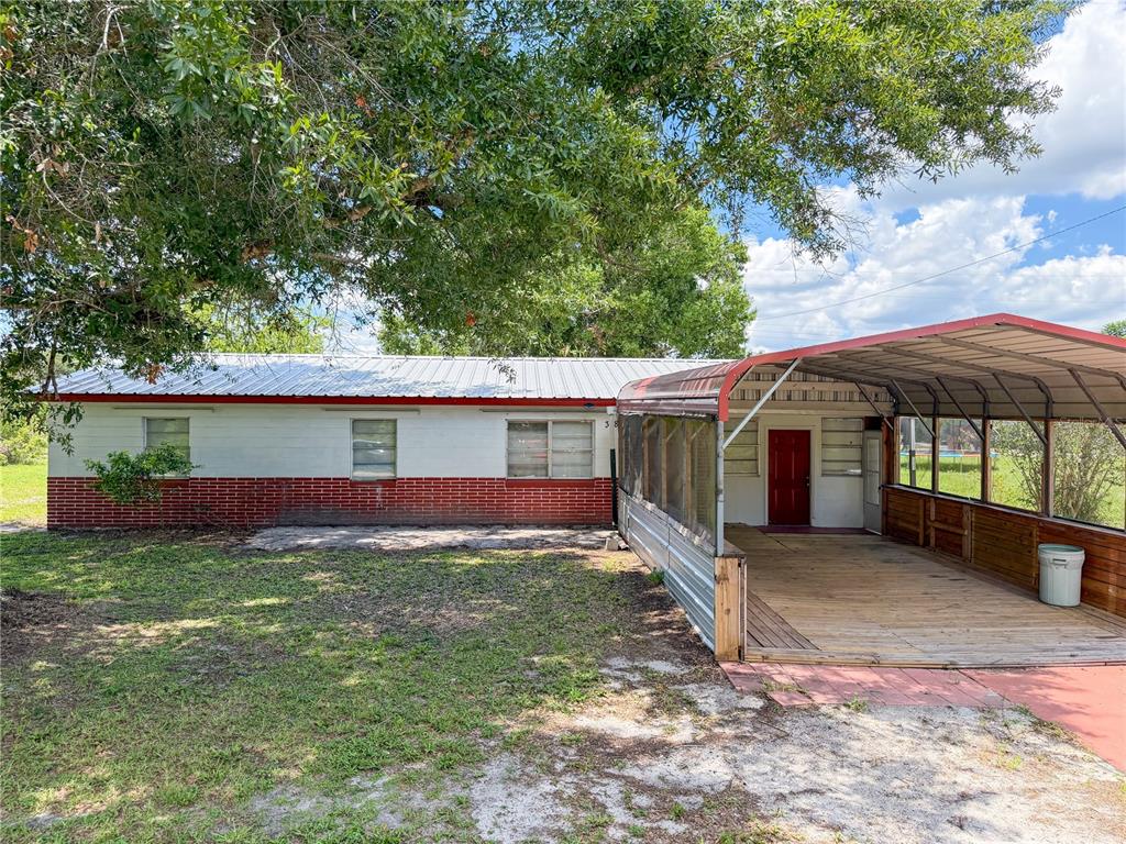A single-story house with a brick and white exterior features a large attached metal carport — 308 CENTRAL AVENUE, FROSTPROOF, FL