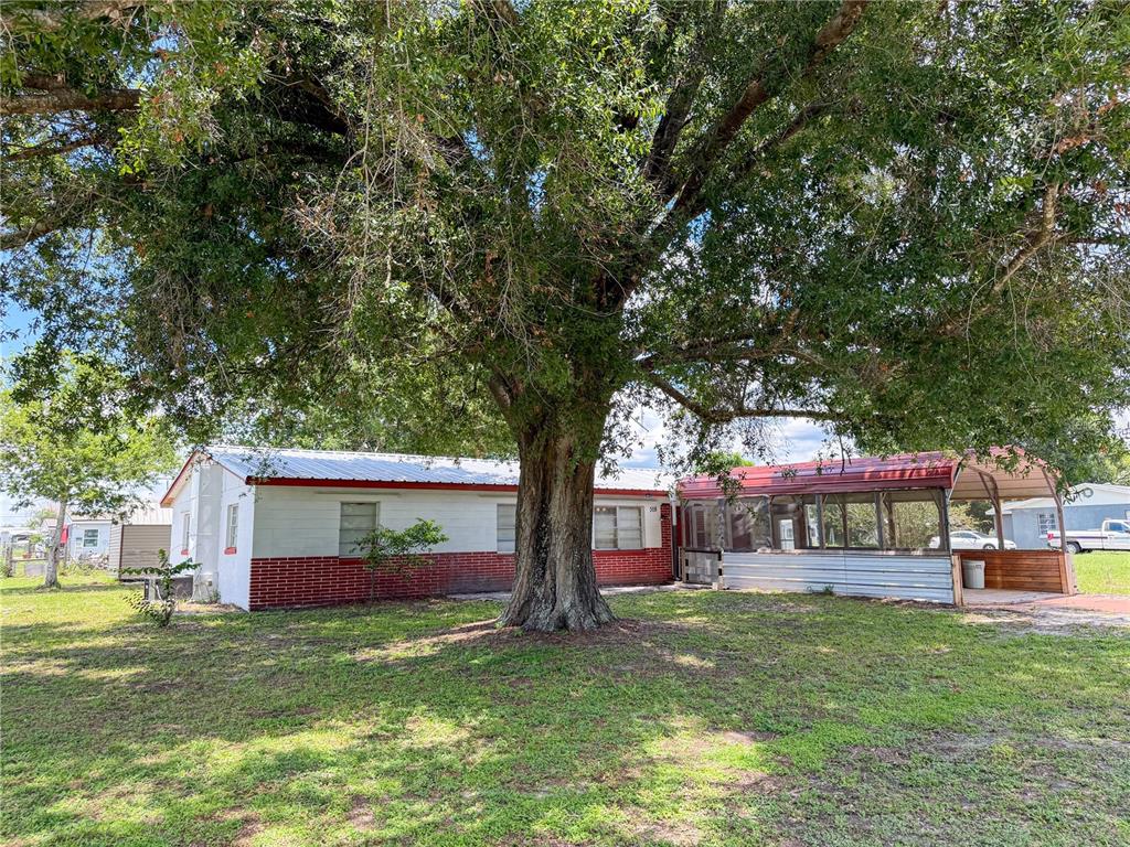 A single-story house with a large tree in the front yard and a metal carport — 308 CENTRAL AVENUE, FROSTPROOF, FL
