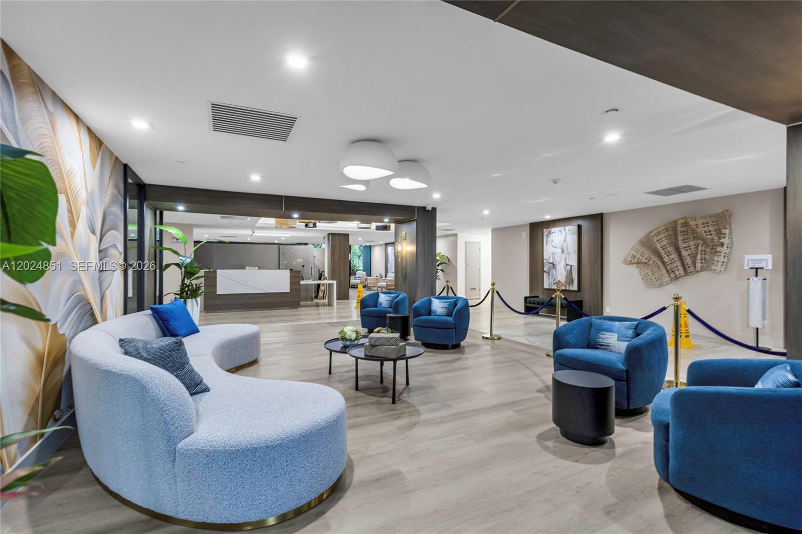 A modern lobby features a curved light blue sofa, blue armchairs, and wood-look flooring — 4200 Hillcrest Dr # 504, Hollywood FL 33021, HOLLYWOOD, FL