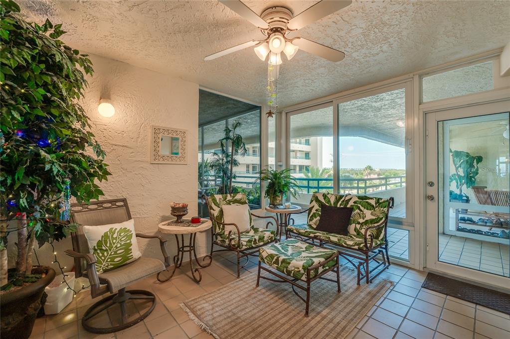 A sunroom features tile flooring, a ceiling fan, tropical-patterned furniture, and large sliding glass doors — 4555 S ATLANTIC AVENUE UNIT 4304, PORT ORANGE, FL