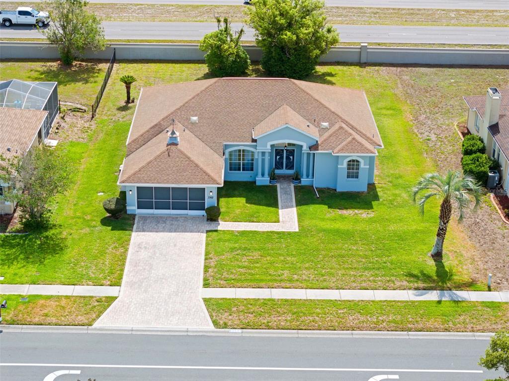 An aerial view shows a light blue single-story house with a paved driveway and walkway — 3362 ST IVES BOULEVARD, SPRING HILL, FL