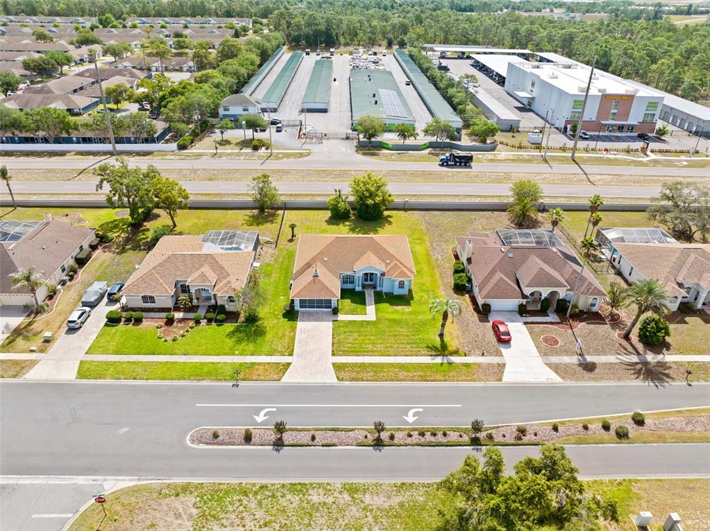 An aerial view shows three suburban houses with driveways facing a street and storage units — 3362 ST IVES BOULEVARD, SPRING HILL, FL