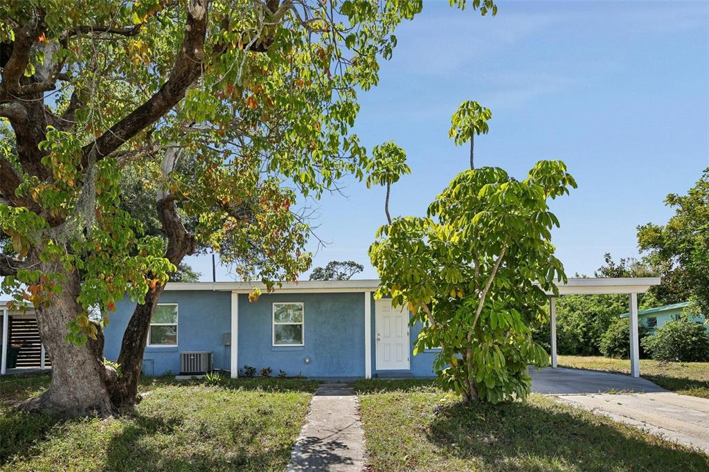 A single-story blue house with a white door, two windows, and an attached carport — 2321 EDNOR STREET, PORT CHARLOTTE, FL
