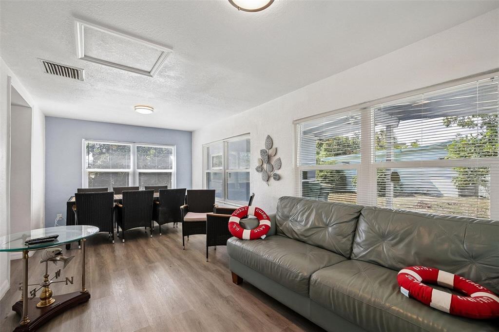 A living and dining area features a gray sofa, a glass table, and wood-look flooring — 2321 EDNOR STREET, PORT CHARLOTTE, FL