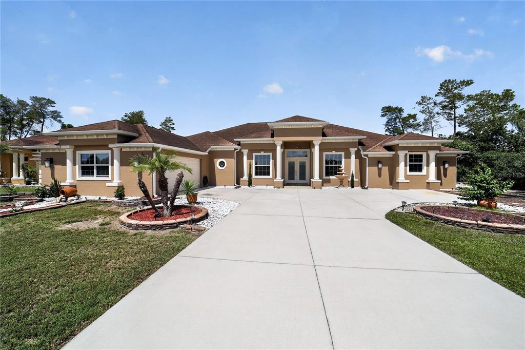 A single-story tan house with a large concrete driveway and white columns — 10202 SW 41ST TERRACE, OCALA, FL