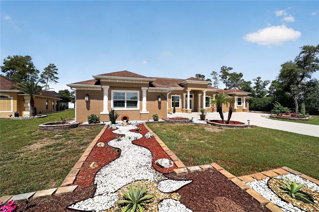A tan single-story house features a decorative rock garden path in the front yard — 10202 SW 41ST TERRACE, OCALA, FL