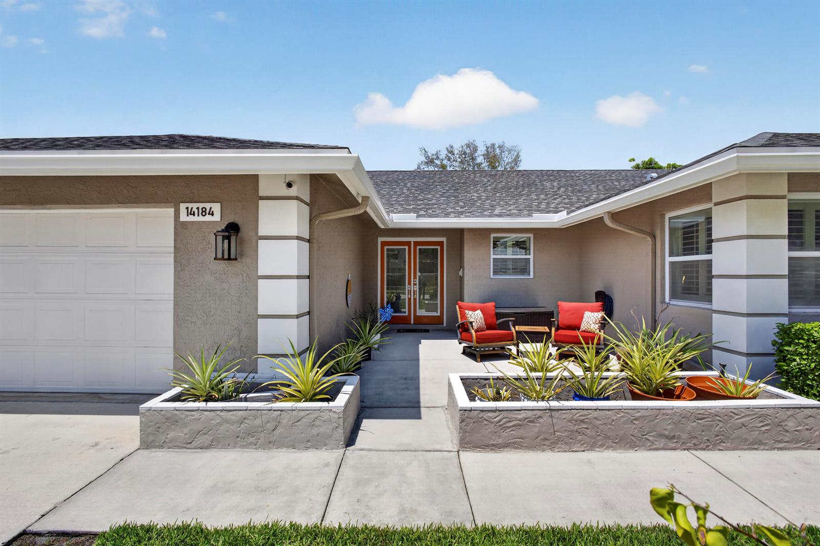 The exterior of a single-story house features a front patio with two red chairs — 14184 Aster Avenue, Wellington FL 33414, WELLINGTON, FL