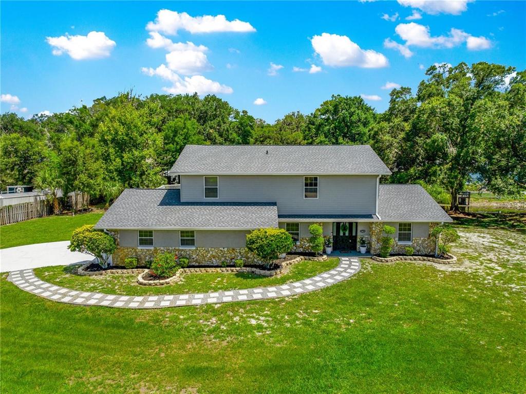 A two-story house with gray siding, stone accents, and a curved stone walkway in front — 15621 SE 103RD TERRACE, SUMMERFIELD, FL