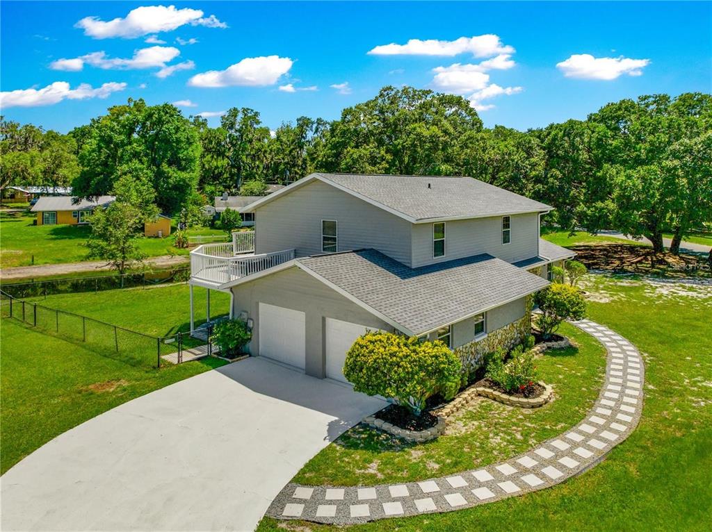 An elevated two-story house with a two-car garage, a deck, and a stone-accented exterior — 15621 SE 103RD TERRACE, SUMMERFIELD, FL