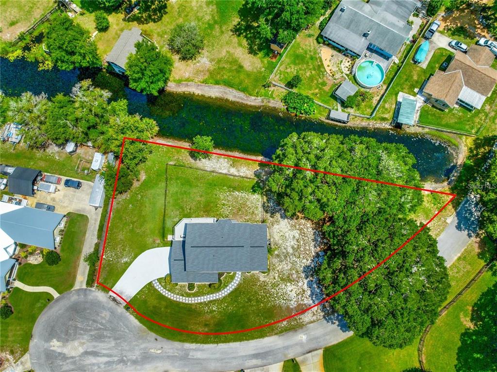 An aerial view shows a house with a red property boundary line on a lot — 15621 SE 103RD TERRACE, SUMMERFIELD, FL