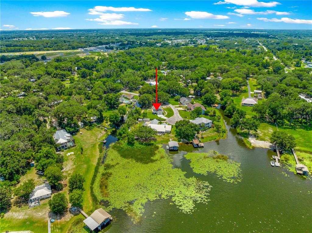 An aerial view shows a house with a red arrow pointing toward it near water — 15621 SE 103RD TERRACE, SUMMERFIELD, FL