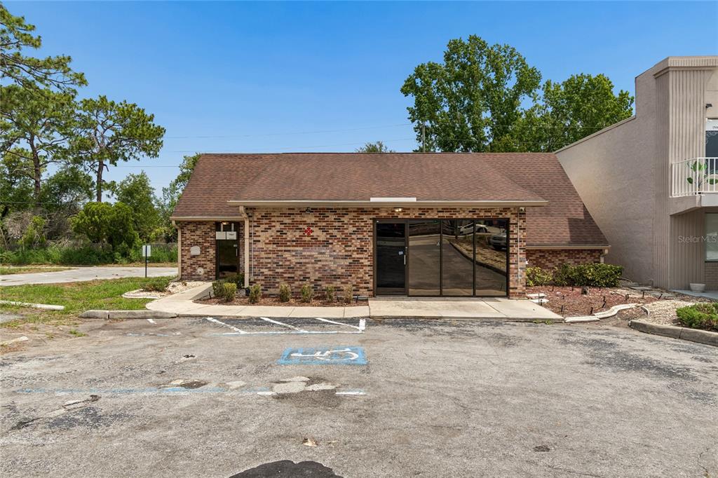 A single-story brick commercial building with a brown shingled roof and a paved parking lot — 11151 SPRING HILL DRIVE, SPRING HILL, FL