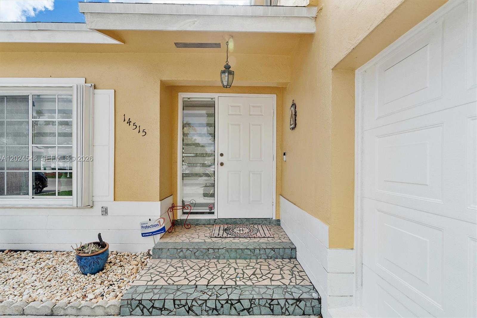The exterior entrance features a white door, tiled steps, and a yellow stucco wall — 14515 SW 139th Ave Cir E, Miami FL 33186, MIAMI, FL