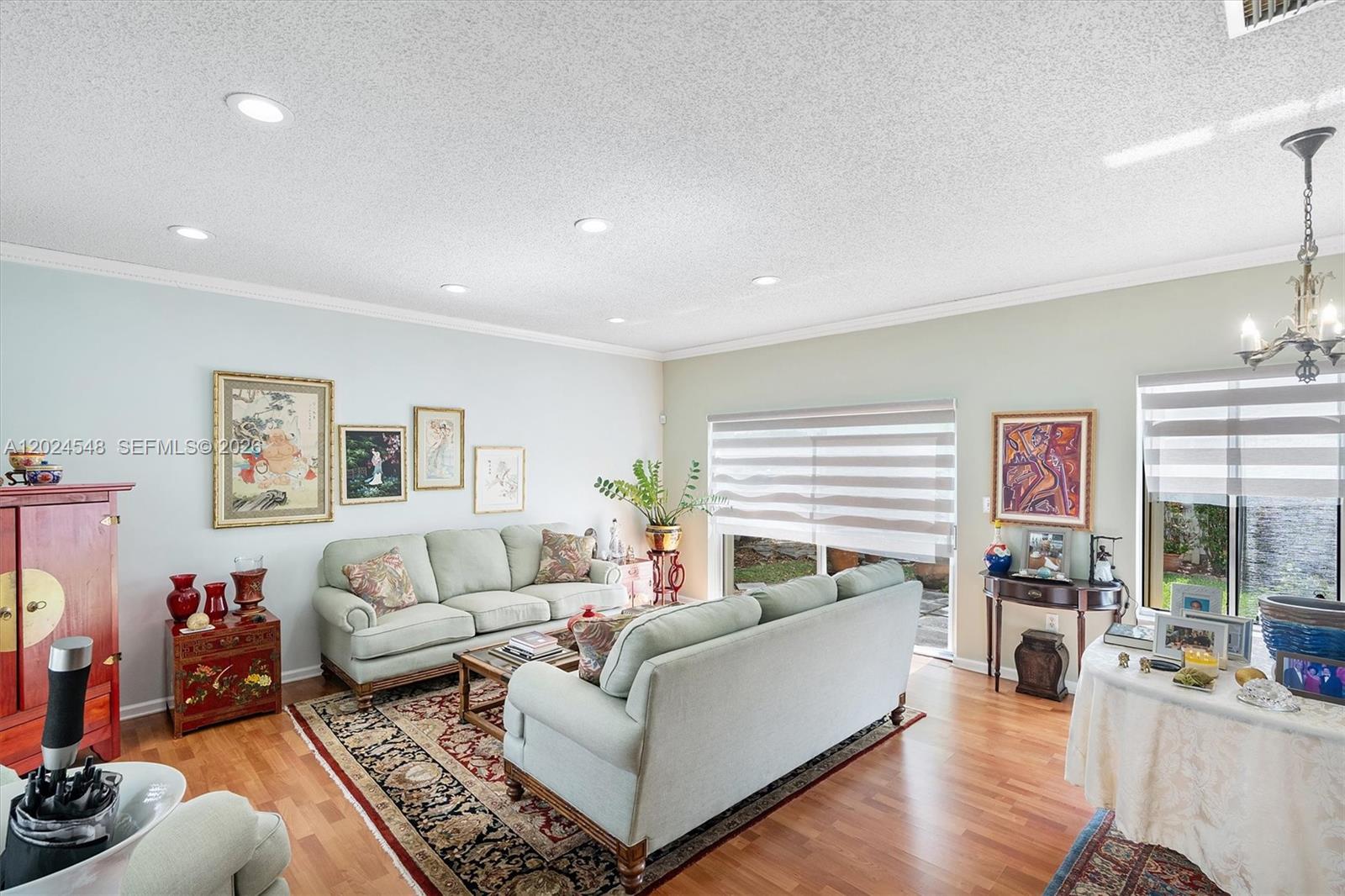 A living room features light green sofas, hardwood floors, a patterned area rug, and artwork — 14515 SW 139th Ave Cir E, Miami FL 33186, MIAMI, FL