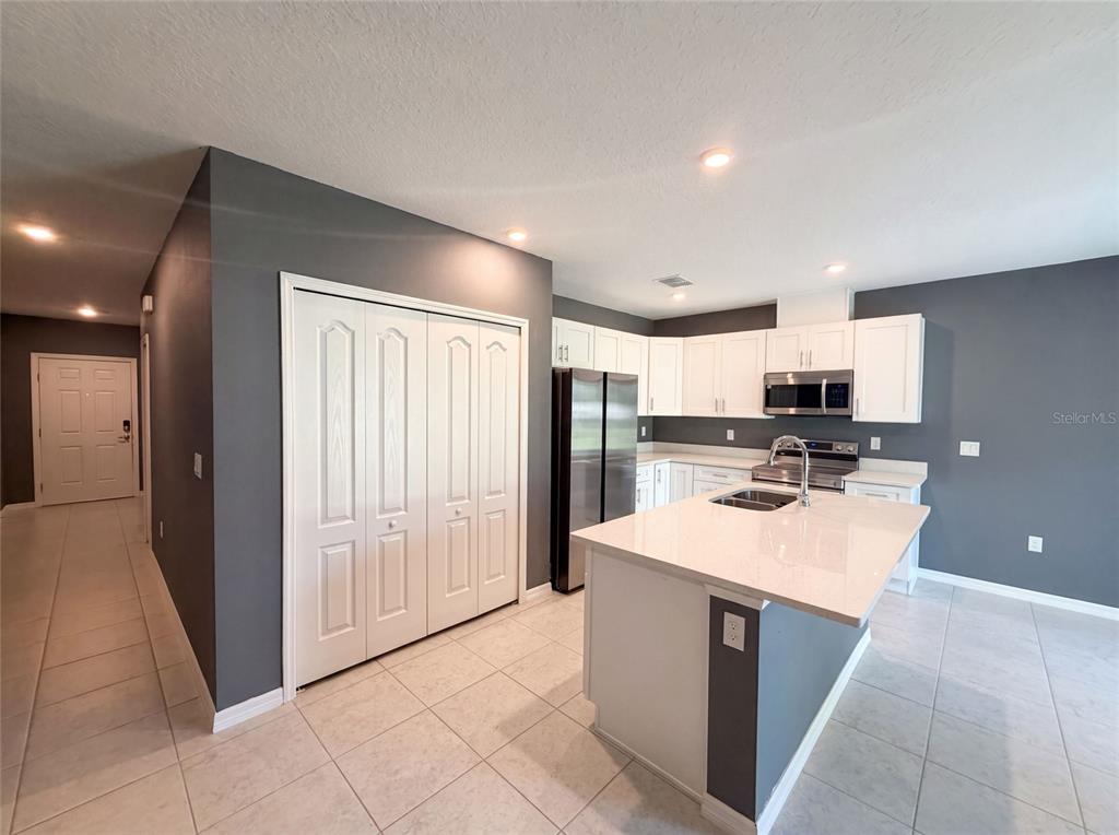 A kitchen features white cabinets, stainless steel appliances, a center island, and dark gray walls — 1443 GENERAL CUSTER AVENUE, DAYTONA BEACH, FL