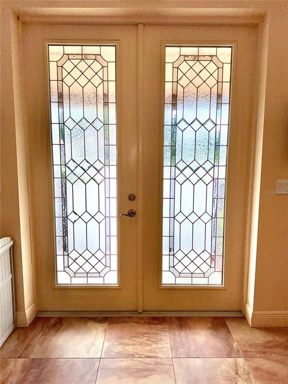 A pair of off-white double doors with decorative leaded glass inserts and tile flooring — 308 DAL HALL BOULEVARD, LAKE PLACID, FL