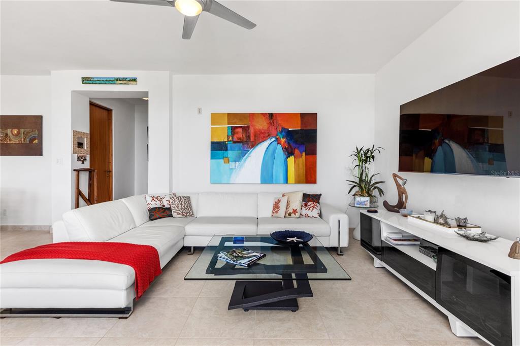 A living room features a white sectional sofa, glass coffee table, and wall-mounted television — 9000 RIO MAR UNIT 263, RIO GRANDE, PR