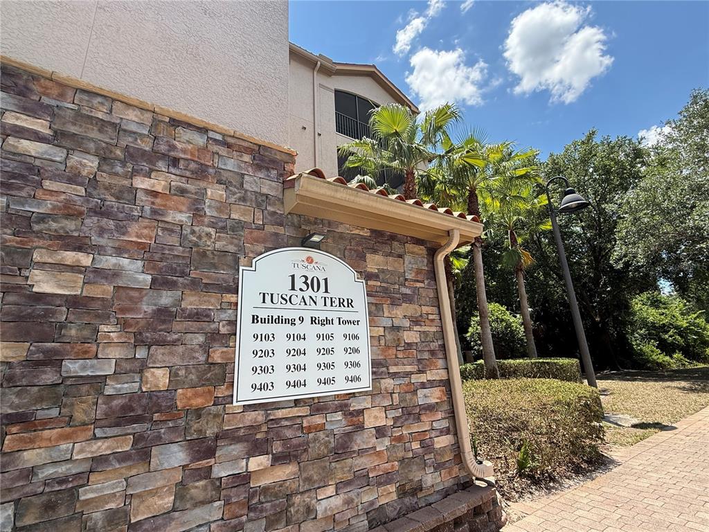 A stone-clad building exterior features a directory sign listing apartment numbers for the right tower — 1301 TUSCAN TERRACE UNIT 9306, DAVENPORT, FL