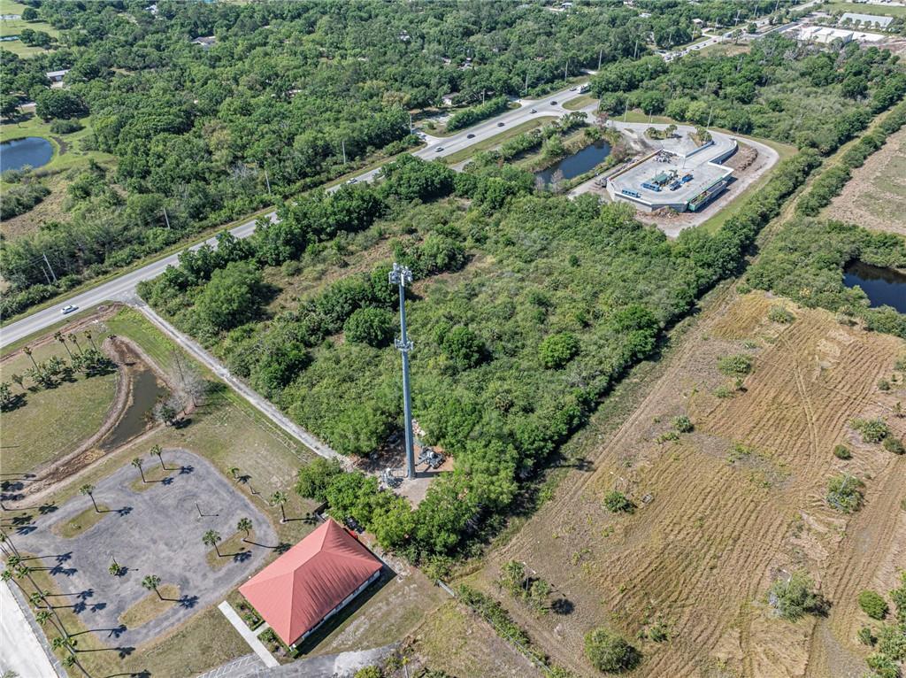 An aerial view shows a cell tower situated on a wooded lot near a road — 12498 County Road 512, Fellsmere FL 32948, FELLSMERE, FL