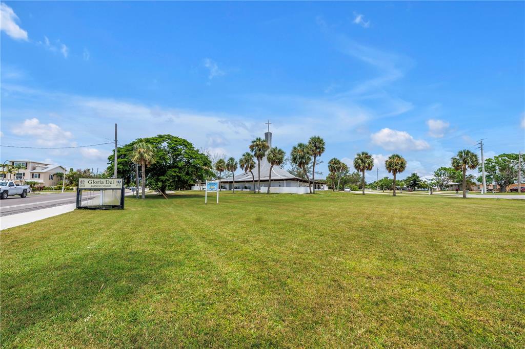 A church building with a tall steeple stands on a large, grassy lot with palm trees — 6608 MARINA DRIVE, HOLMES BEACH, FL