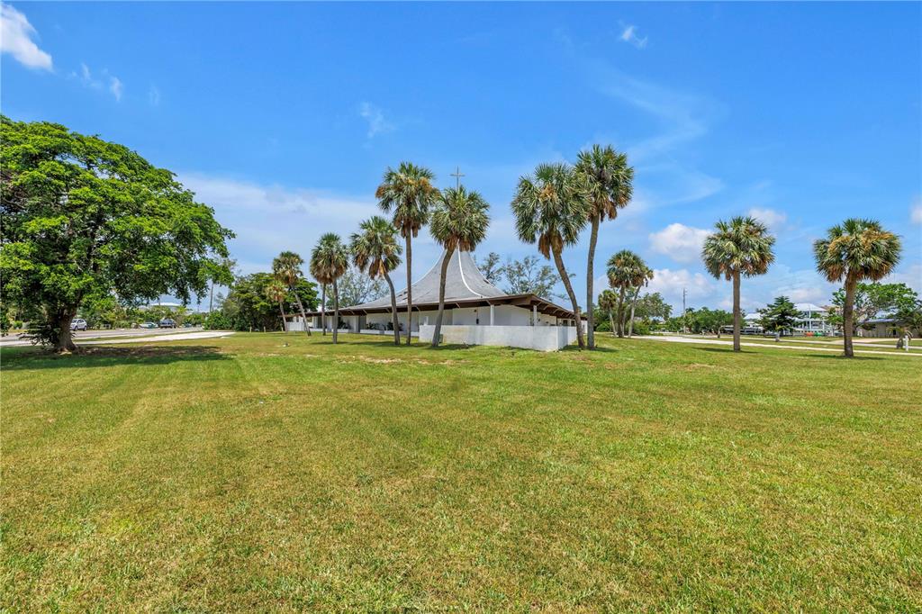 A white church building with a conical roof stands behind palm trees in a field — 6608 MARINA DRIVE, HOLMES BEACH, FL