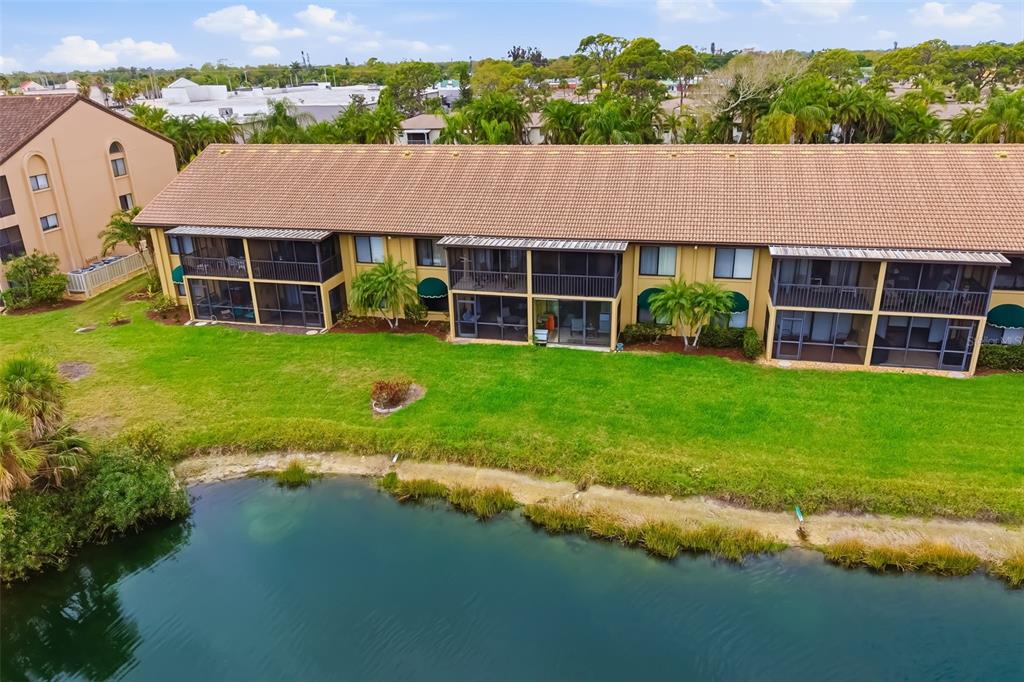 An aerial view shows a multi-story apartment building with screened balconies overlooking a pond — 5543 ASHTON WAY UNIT 5543, SARASOTA, FL