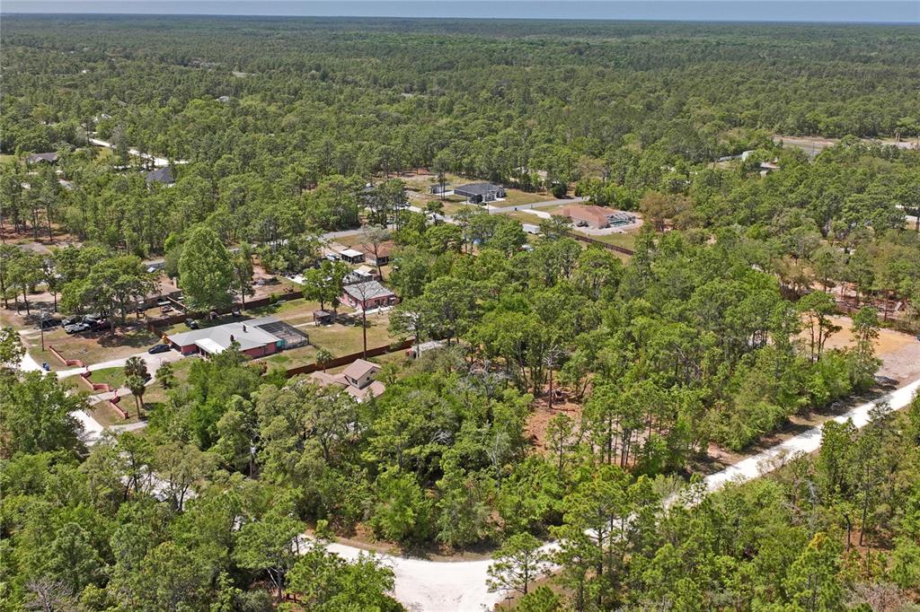 An aerial view shows several houses surrounded by dense forest and a dirt road — 0 YELLOWSTONE AVENUE, WEEKI WACHEE, FL