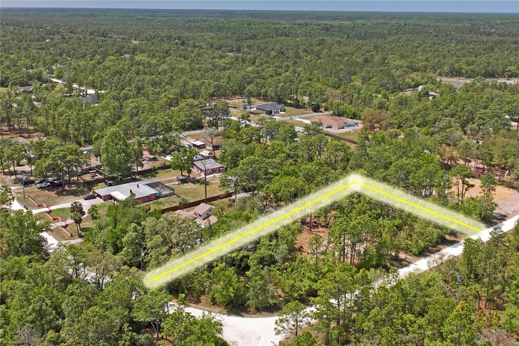An aerial view shows a wooded residential lot outlined in yellow near a dirt road — 0 YELLOWSTONE AVENUE, WEEKI WACHEE, FL