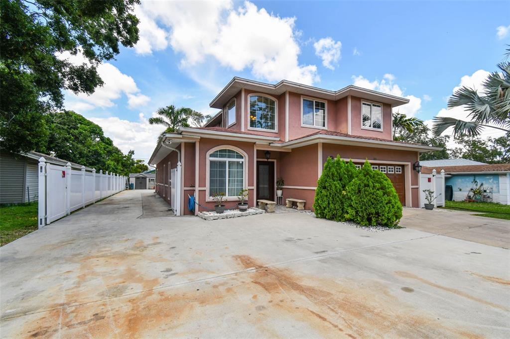 A two-story, stucco-finished house with a concrete driveway and a white vinyl fence — 3225 71ST AVENUE N, ST PETERSBURG, FL