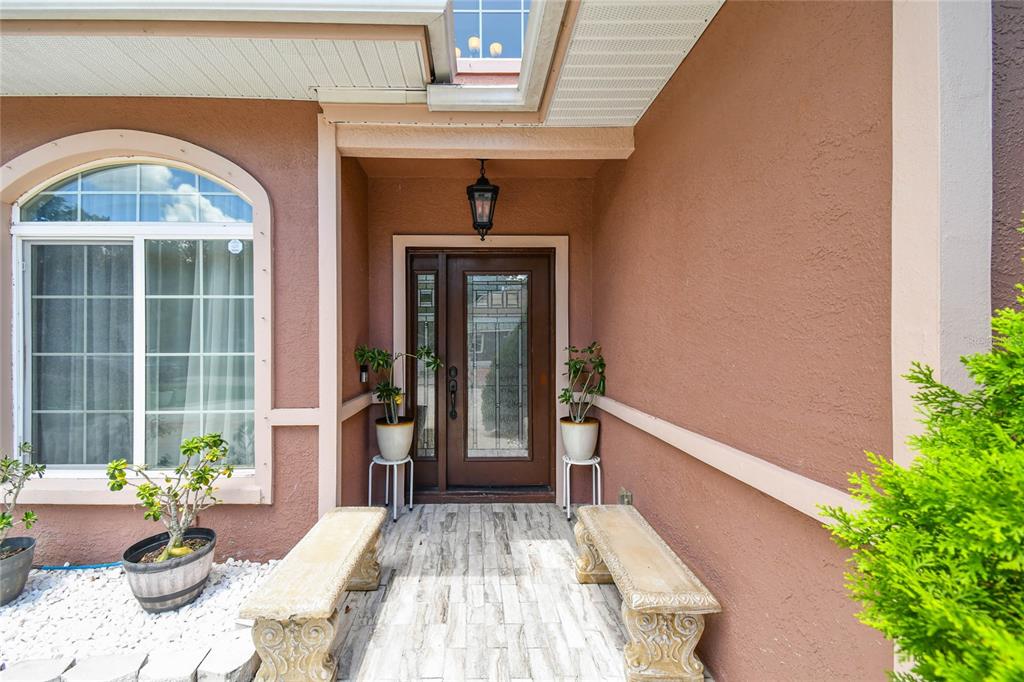 A brown front door with a glass insert sits under a covered entryway with benches — 3225 71ST AVENUE N, ST PETERSBURG, FL