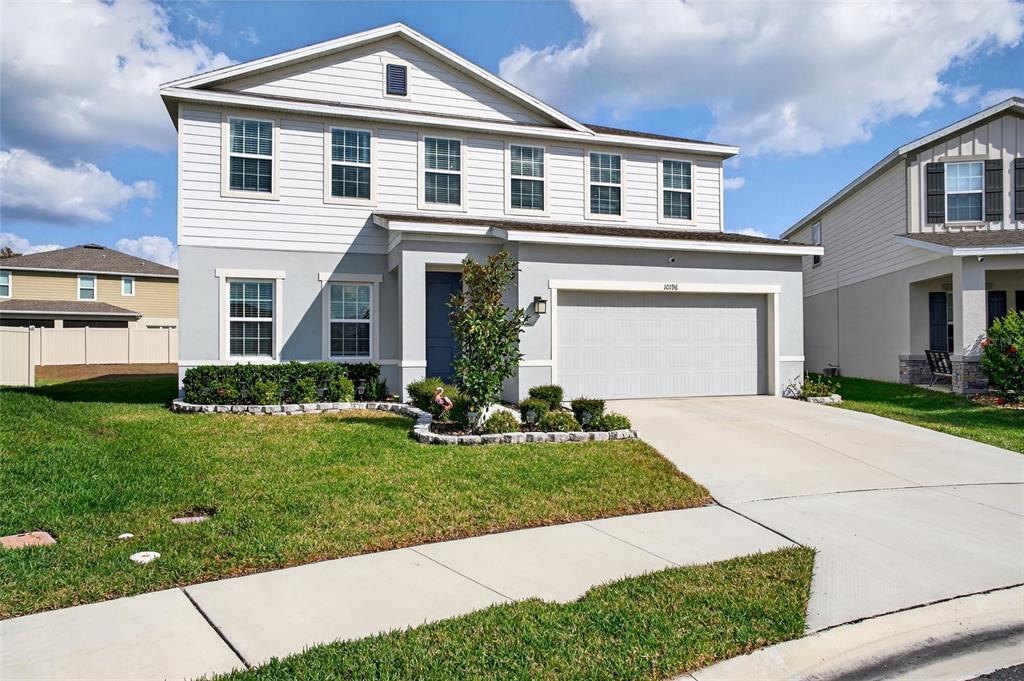 A two-story suburban house with a gray stucco and white siding exterior and garage — 10196 AGAVE COURT, LAND O LAKES, FL