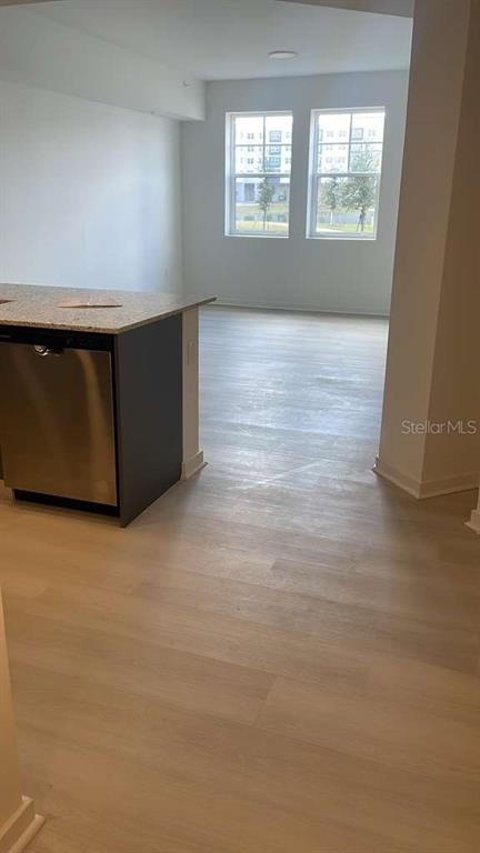 A kitchen island with a stainless steel dishwasher faces a bright, open-concept living area — 5587 MILLENIA PARK BOULEVARD UNIT 111, ORLANDO, FL