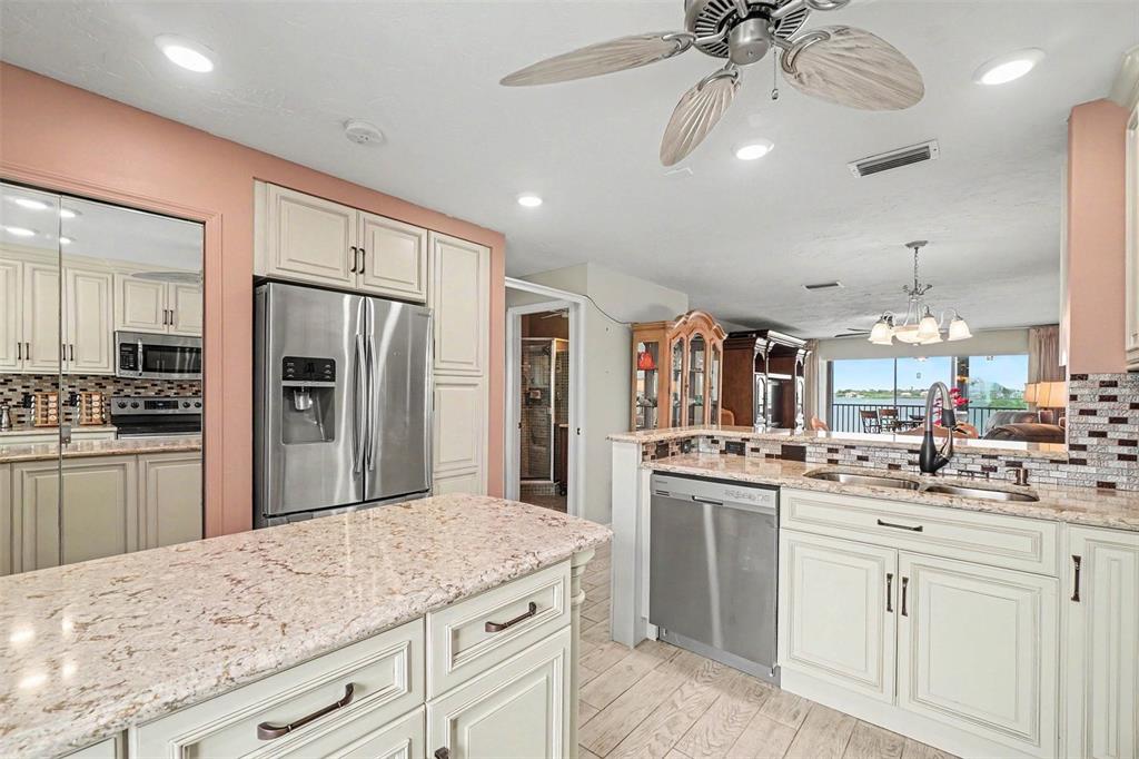 A kitchen features cream cabinets, granite countertops, stainless steel appliances, and a view of water — 9011 MIDNIGHT PASS ROAD UNIT 329, SARASOTA, FL