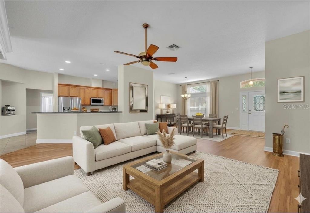 An open-concept living room features a sectional sofa, a wooden coffee table, and a kitchen — 8923 BRIDGEPORT BAY CIRCLE, MOUNT DORA, FL
