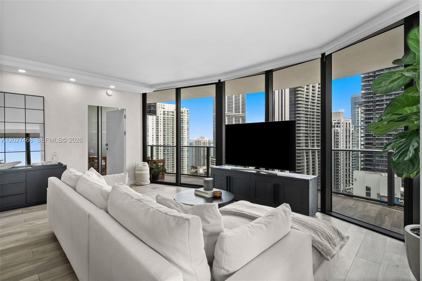 A modern living room features a white sectional sofa, dark media console, and floor-to-ceiling windows — 801 S Miami Ave # 2901, Miami FL 33130, MIAMI, FL