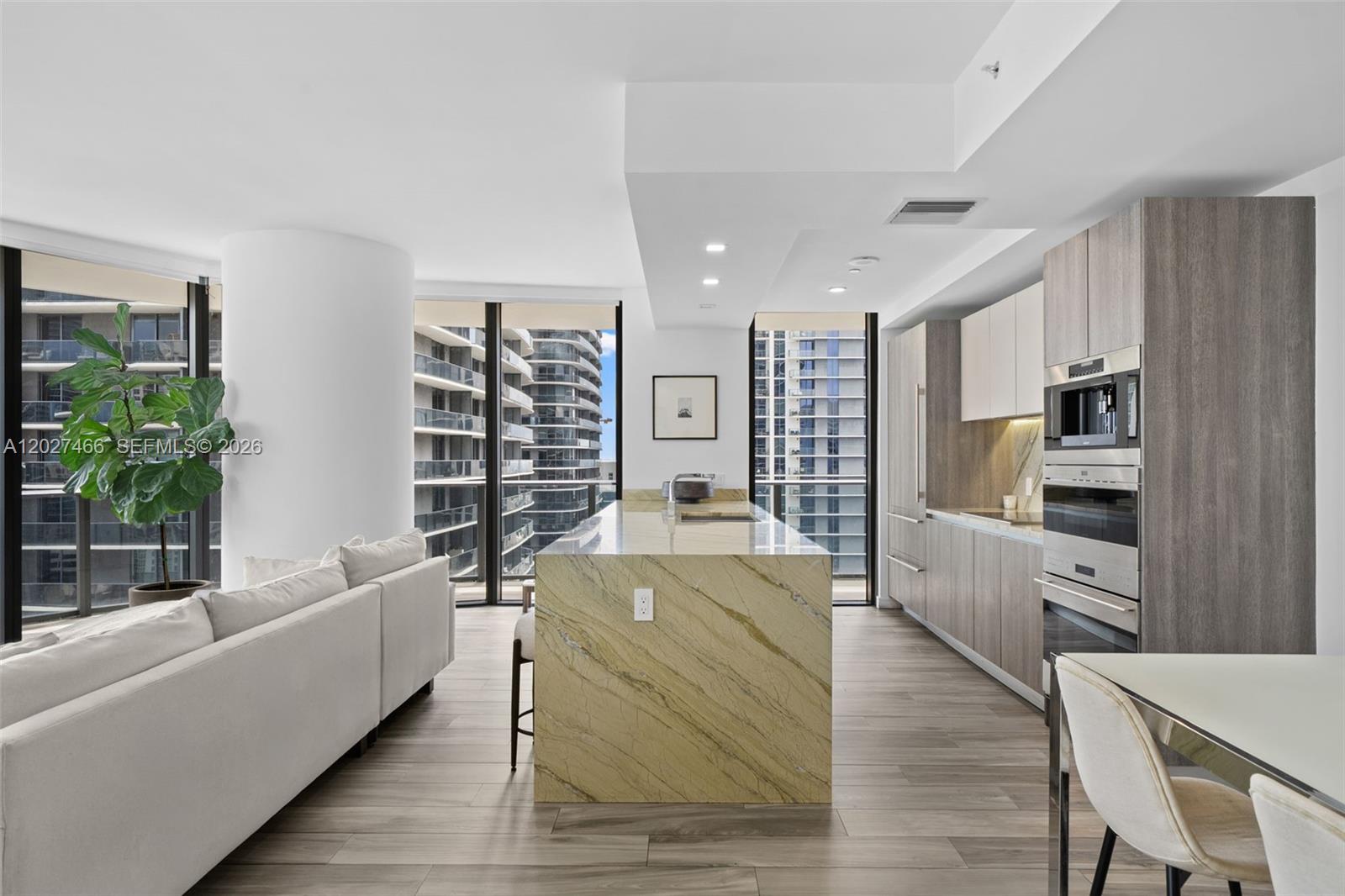 A modern kitchen and living area features a stone island, wood cabinetry, and floor-to-ceiling windows — 801 S Miami Ave # 2901, Miami FL 33130, MIAMI, FL
